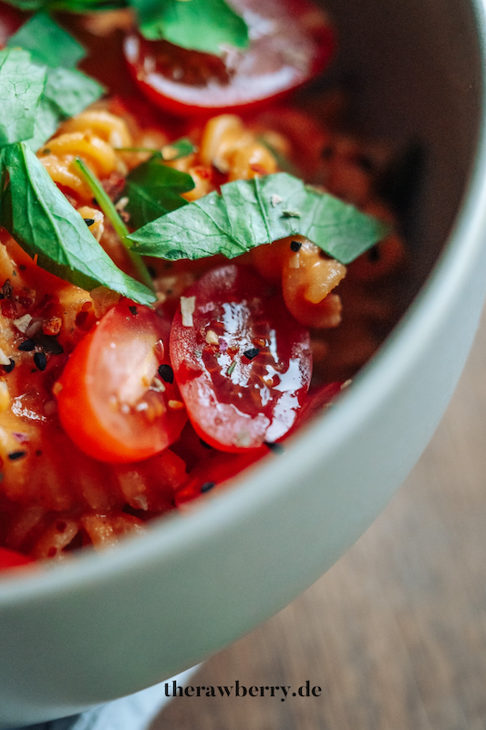 Nudeln in Schüssel mit Paprikasoße mit Tomaten und Koriander