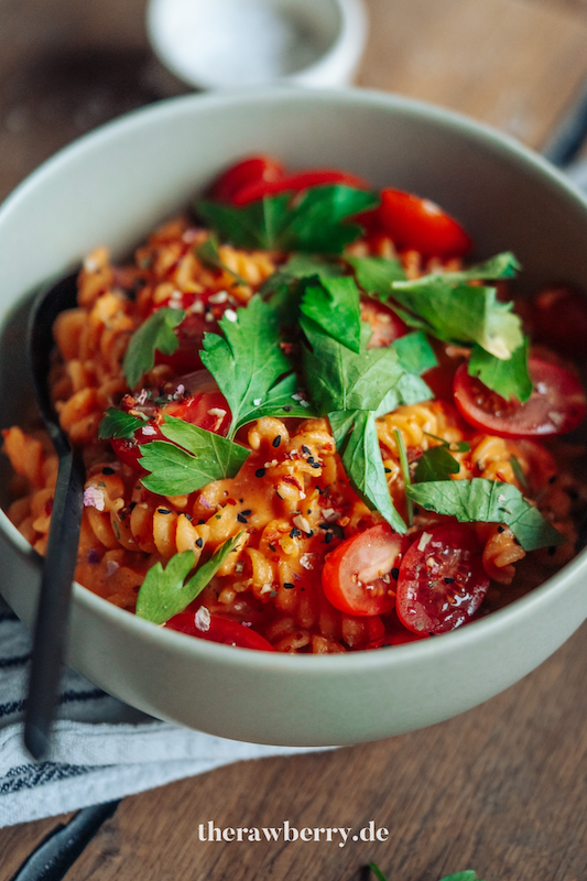 Nudeln in Schüssel mit Paprikasoße mit Tomaten und Koriander