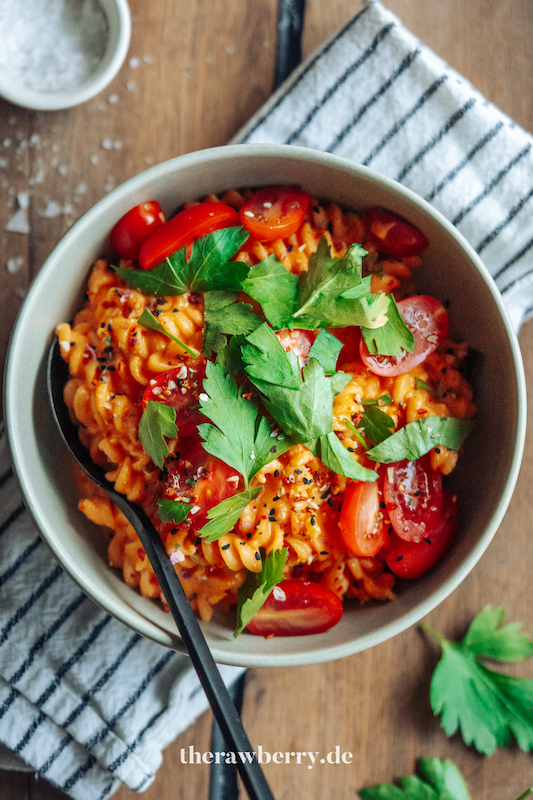 Nudeln in Schüssel mit Paprikasoße mit Tomaten und Koriander