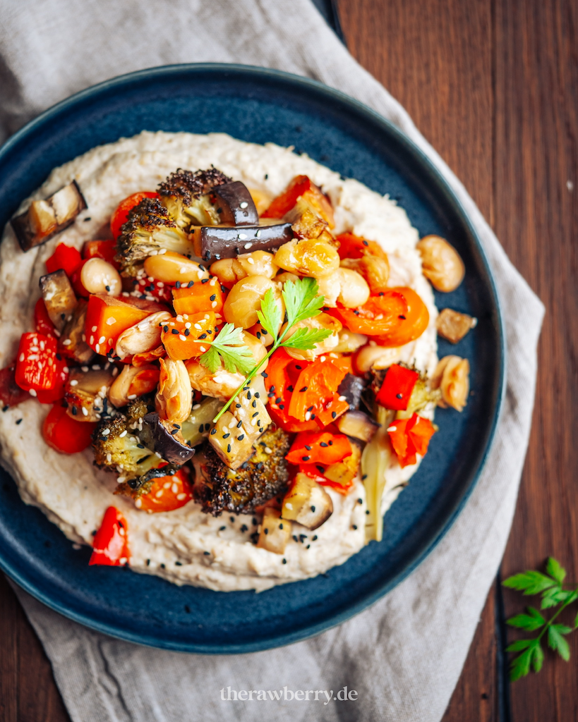 grillgemüse auf hummus auf dunklem Teller