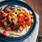 Grillgemüse auf weiße Bohnen Hummus auf dunklem Teller