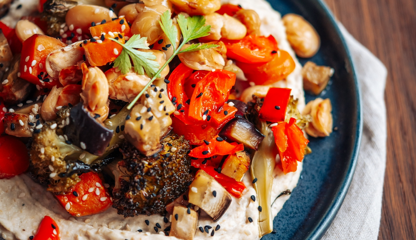 Grillgemüse auf weiße Bohnen Hummus auf dunklem Teller