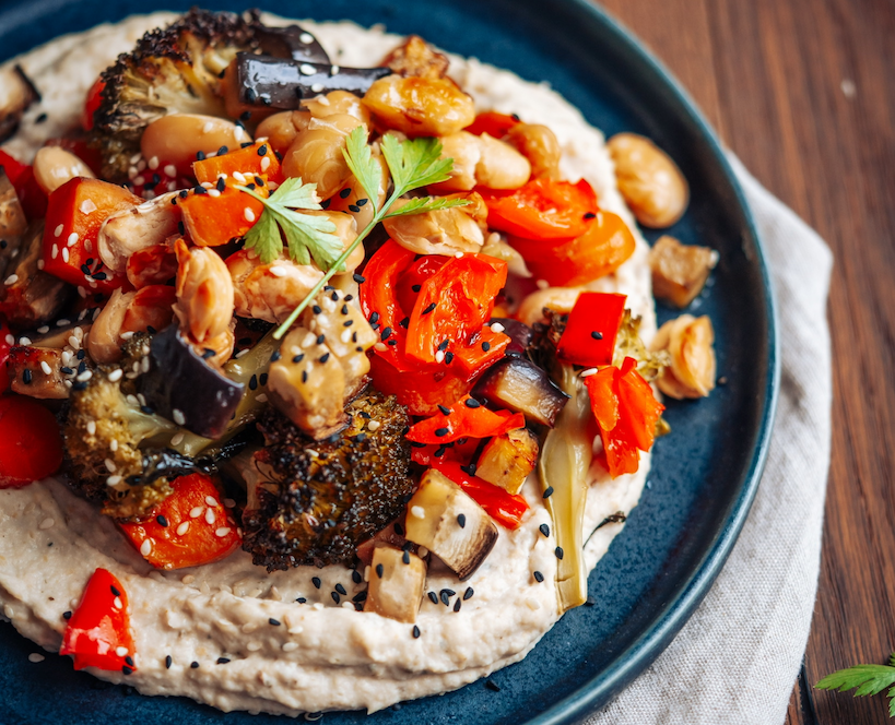 Grillgemüse auf weiße Bohnen Hummus auf dunklem Teller